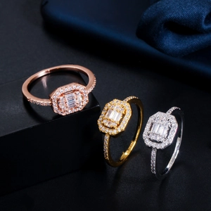 Macro view of three halo engagement rings in rose gold, gold, and silver with pavé zircon
