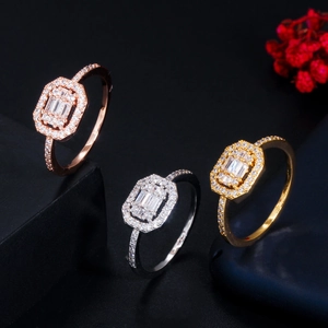 Close-up of three geometric gold and silver rings with pave-set zircon on black stone
