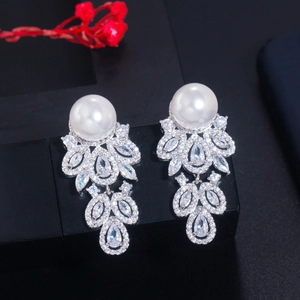 Elegant pearl and zircon drop earrings set in silver finish on a black display