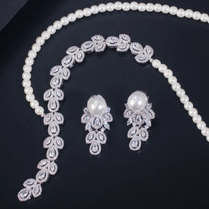 Elegant silver jewelry set with pearls and leaf-shaped zircons on a dark background