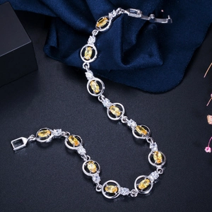 Detailed macro view of silver-toned chain bracelet with yellow oval-cut cubic zirconia