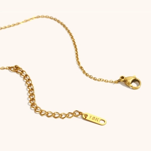 Macro detail of 18K gold plated necklace with lobster clasp and engraved hallmark