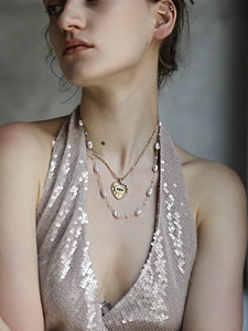 Detalle de collar con colgante de corazón bañado en oro 18K y cadena de perlas