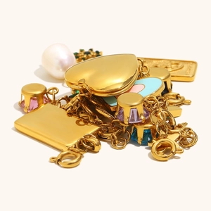 Dettaglio macro di ciondoli a molla placcati in oro 18K con gemme colorate e perla