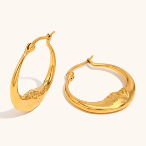 Macro detail of 18K gold plated hoop earrings featuring embossed crescent moon faces