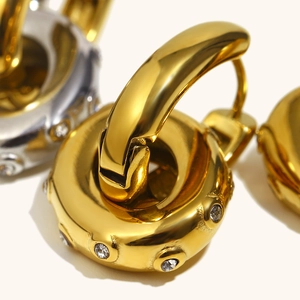 Polierte Creolen aus 18K Gold und Silber mit runden Zirkonia auf warmem Hintergrund