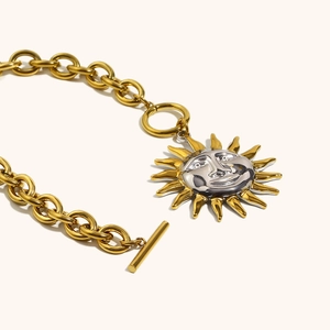 Detailed view of dual-tone sun pendant necklace with T-bar toggle clasp and thick chain