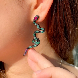 Close-up of a snake-shaped earring in gunmetal with green and pink zircons on a model