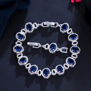 Silver-toned chain bracelet with oval sapphire blue stones and adjustable fold-over clasp