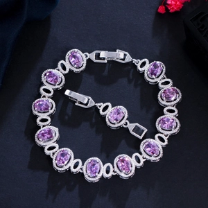 Detail shot of brass 18K gold plated bracelet with purple zircons on black texture