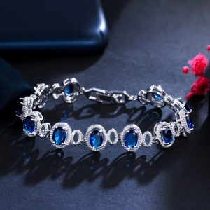 Macro detail of silver-tone link bracelet with oval blue sapphires and zircon halo