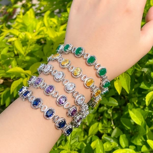 Elegant silver-toned bracelets with oval sapphire-cut colorful zircons on a model's wrist