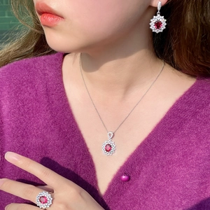 Ruby red jewelry set featuring necklace earrings and ring on a model in sunlight