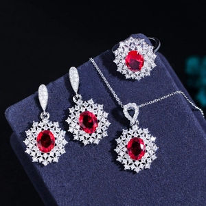 Detailed view of red ruby jewelry set with halo zirconia on dark velvet background