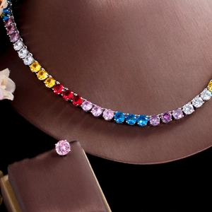 Detalle macro de collar de circonita arcoíris y pendiente rosa en expositor de joyas