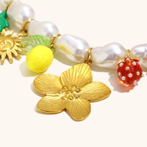 Baroque pearl necklace with gold flower, strawberry and lemon charms on white background