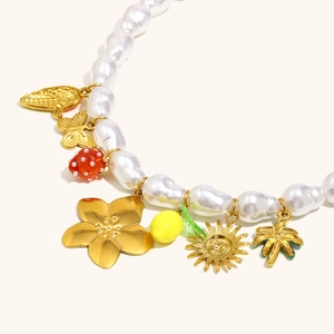 Detail view of Baroque pearl necklace with colorful strawberry and flower charms
