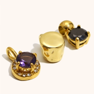 Macro detail of 18K gold plated cylindrical pendants and round purple and black zircon charms