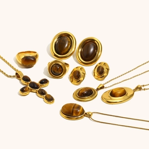 Detail eines 18K vergoldeten Edelstahlschmuck-Sets mit Tigerauge und Kreuzanhängern