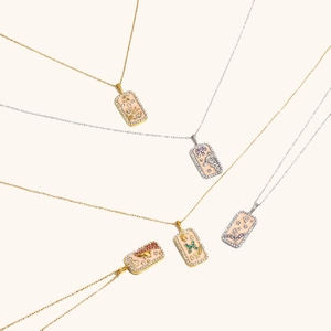 Détail de pendentifs constellation carrés plaqués or 18K avec émail coloré et zircons