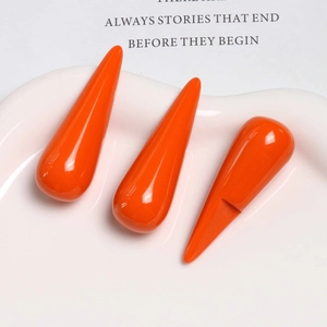 Close-up of three glossy orange teardrop resin charms for DIY earring and hair accessories