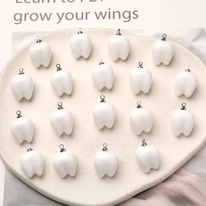 Set of 18 cute white tooth-shaped resin charms for DIY jewelry making on ceramic plate