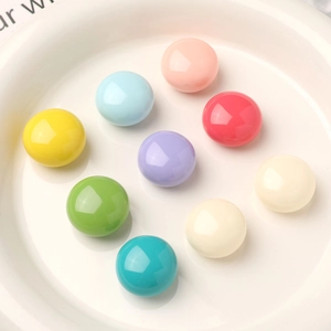 Macro view of assorted pastel resin cabochons in 9 candy colors on a white ceramic tray