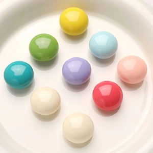 Macro shot of 9 colorful macaron resin cabochons in a white plate for DIY crafts
