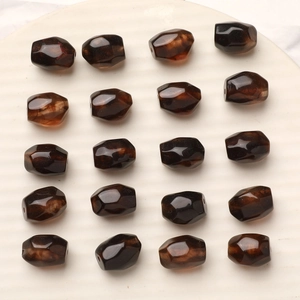 Faceted amber resin barrel beads for DIY jewelry making displayed on a white tray