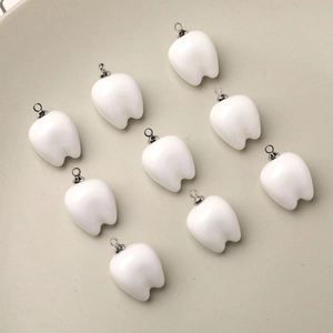 Detailed view of ten glossy resin tooth pendants with silver rings for DIY jewelry