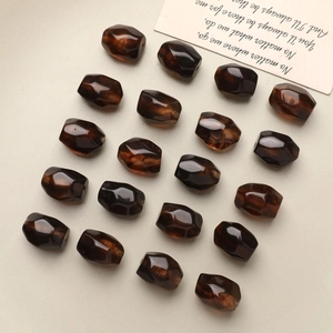 Macro shot of 20 faceted amber brown resin beads arranged on a soft beige background
