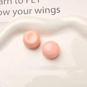 Detailed close-up of glossy pink resin dome cabochons on a white decorative ceramic tray