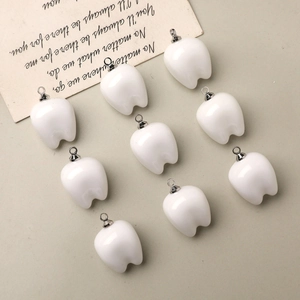 Detailed view of ten cute 3D resin tooth charms with silver loops on aesthetic background