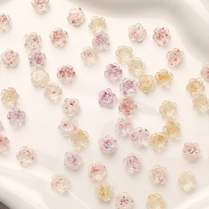 Detailed macro shot of translucent resin camellia nail charms with gold foil flakes
