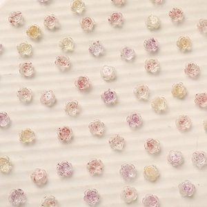 Close-up of 8mm camellia nail art charms with gold leaf and translucent rose textures