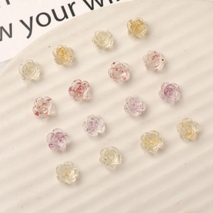 Macro detail of translucent resin flower nail charms with gold foil and glitter finish