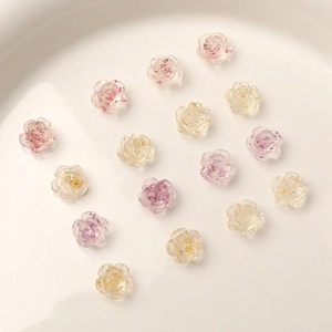 Top view of resin camellia flower charms with gold foil on a white ceramic plate