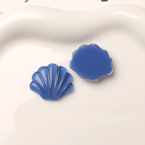 Makroaufnahme von zwei blauen Harzmuscheln mit Rippenstruktur für DIY-Schuhdekoration