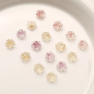 Macro view of translucent 8mm camellia nail charms with gold foil and resin petal textures