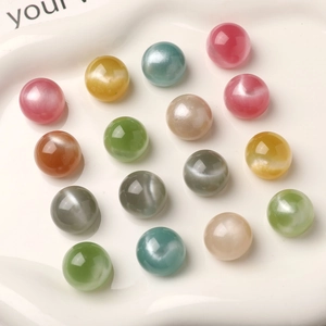 Close-up of colorful round 16mm resin beads with star sand texture in a white tray