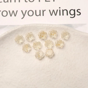 Detailed macro view of 11 translucent resin rose charms with gold foil for DIY nail art