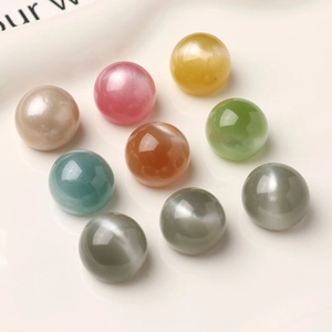 Macro detail of 16mm glitter resin beads with cat-eye luster on a white ceramic tray