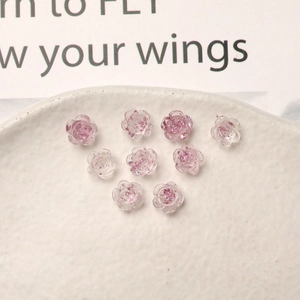 Macro detail of 8mm translucent resin camellia flower nail charms with glitter center