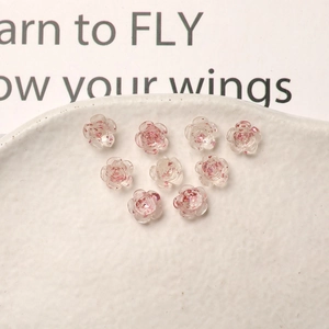 Macro shot of 9 translucent rose charms with gold foil inside for DIY nail art and crafts