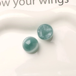 Macro shot of 16mm blue starry resin beads with cat-eye effect on white ceramic tray