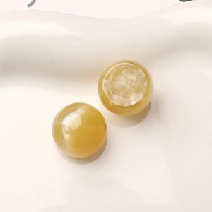 Macro detail of 16mm yellow starry resin cabochons with cat eye effect on white tray