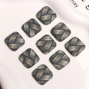 Macro view of nine square fabric-wrapped decorative buttons with twill pattern