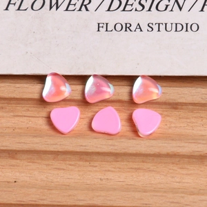 Macro detail of iridescent and pastel pink heart-shaped resin charms for nail art and DIY