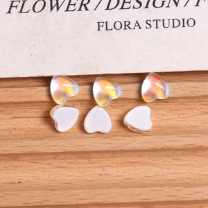 Detailed view of aurora iridescent and solid white heart-shaped charms on a wooden surface