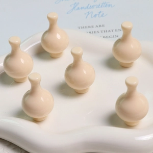 Primo piano di 6 mini vasi in resina bianco crema su un vassoio di ceramica